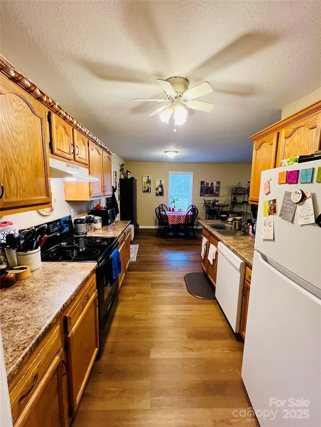 kitchen with ceiling fan, white appliances, wood-type flooring, and a textured ceiling