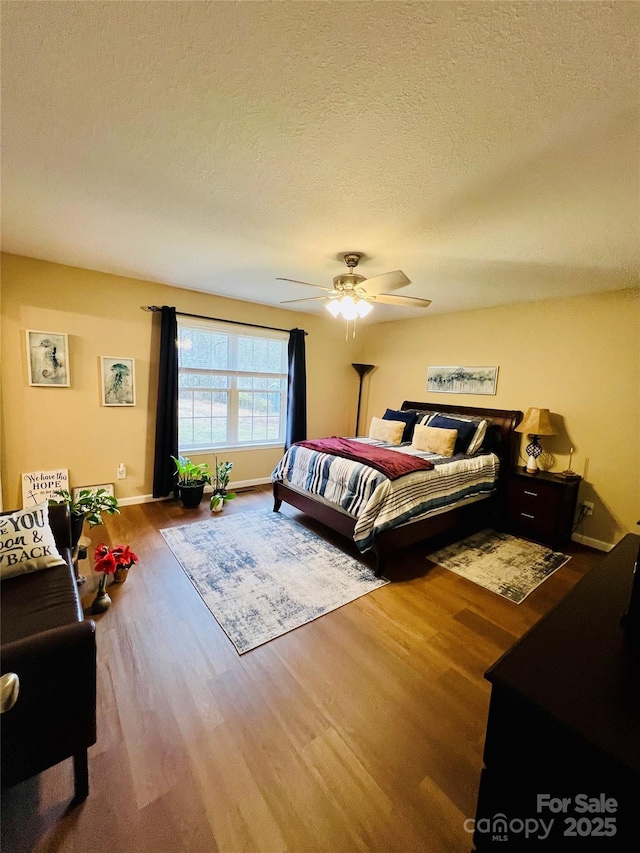 bedroom featuring wood-type flooring, a textured ceiling, and ceiling fan