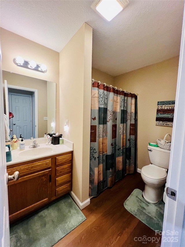 bathroom featuring toilet, wood-type flooring, a textured ceiling, vanity, and curtained shower