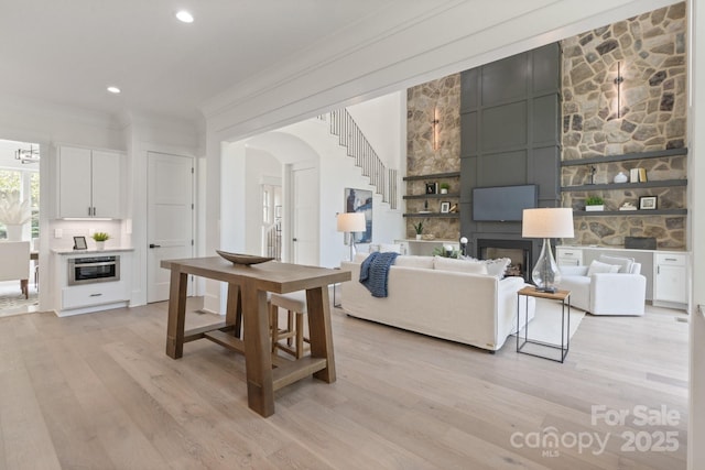 living room featuring a fireplace, crown molding, and light hardwood / wood-style flooring