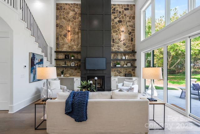 living room with wood-type flooring, a large fireplace, and a high ceiling