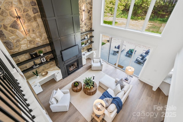 living room with hardwood / wood-style flooring, a towering ceiling, and a fireplace