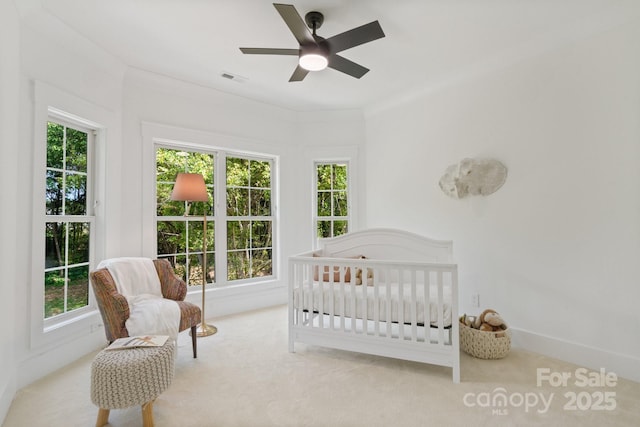 carpeted bedroom with a nursery area and ceiling fan