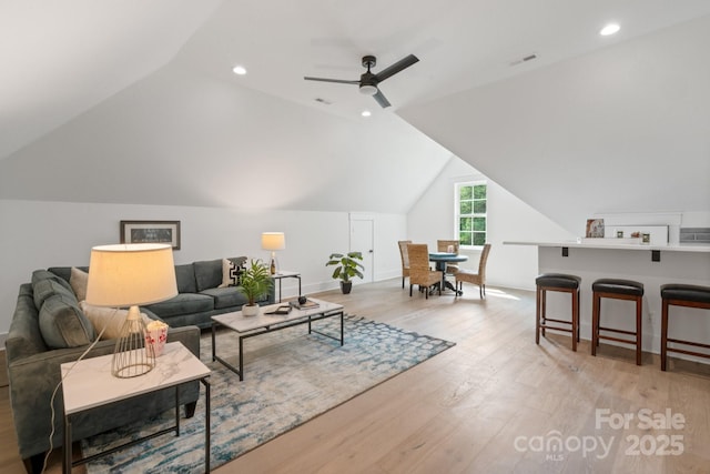 living room featuring ceiling fan, vaulted ceiling, and light hardwood / wood-style flooring