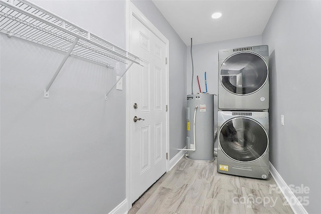 clothes washing area featuring light hardwood / wood-style floors, electric water heater, and stacked washer / dryer