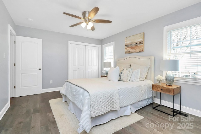 bedroom with ceiling fan, a closet, dark hardwood / wood-style flooring, and multiple windows