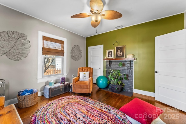 living area with a brick fireplace, hardwood / wood-style floors, and ceiling fan