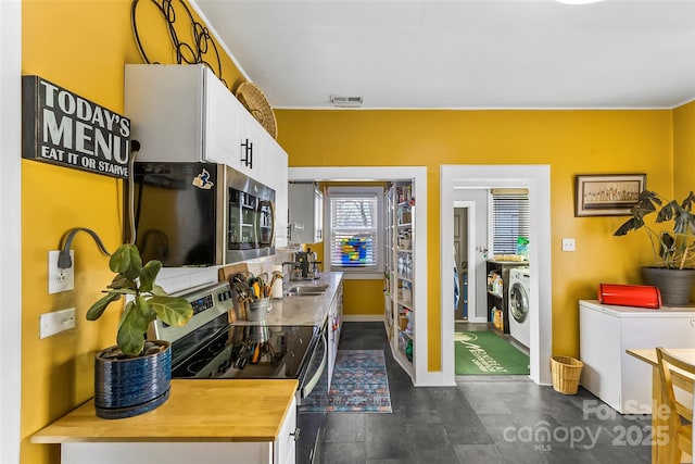 kitchen with stainless steel appliances, separate washer and dryer, white cabinets, and butcher block countertops