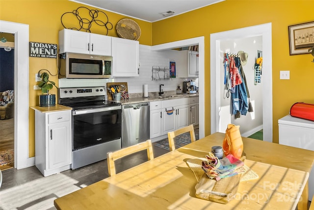 kitchen featuring stainless steel appliances, white cabinetry, sink, and backsplash