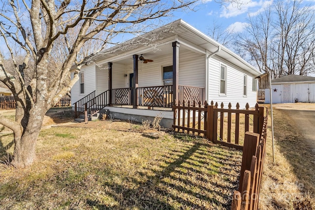 view of front facade featuring a porch, an outbuilding, a garage, ceiling fan, and a front lawn