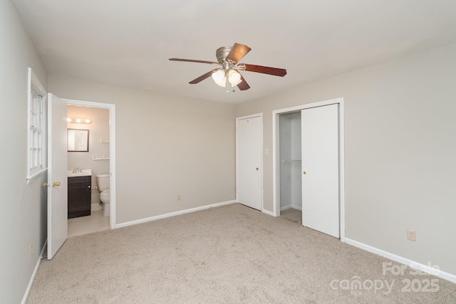 unfurnished bedroom featuring ensuite bathroom, light colored carpet, ceiling fan, and a closet