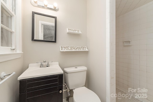 bathroom featuring tiled shower, vanity, and toilet