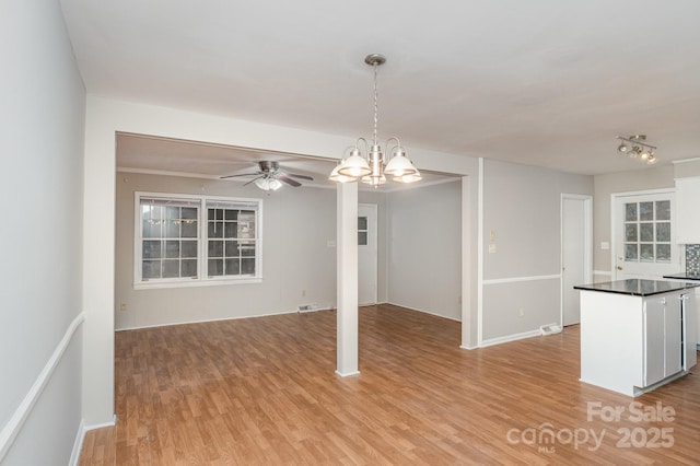 interior space with ceiling fan with notable chandelier and light hardwood / wood-style flooring