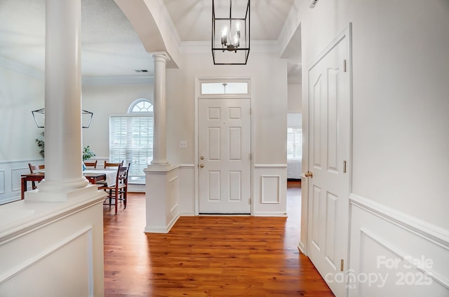 entryway featuring hardwood / wood-style flooring, ornamental molding, and decorative columns