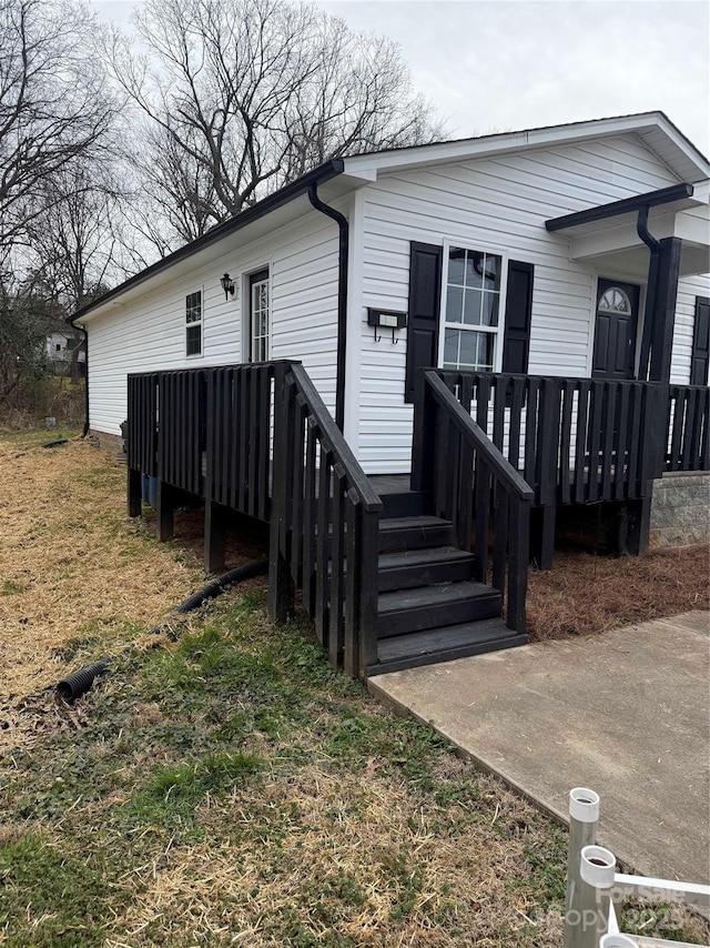 view of front facade featuring a wooden deck and a front yard