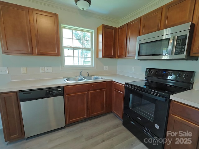 629 S Caldwell St, Salisbury, NC 28144 - kitchen featuring appliances with stainless steel finishes, light wood-style floors, light countertops, ornamental molding, and brown cabinetry