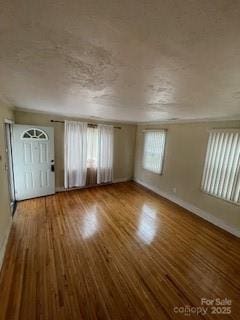 unfurnished living room with a textured ceiling, plenty of natural light, and wood finished floors