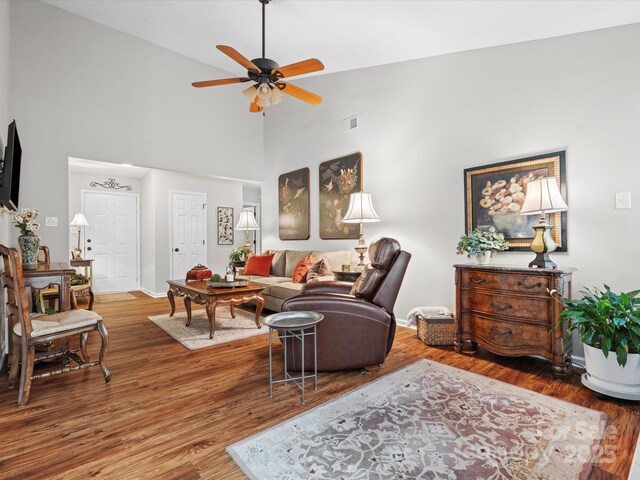 living room with wood-type flooring, high vaulted ceiling, and ceiling fan