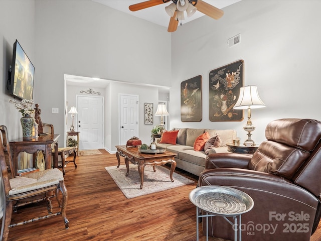 living room with a towering ceiling, wood-type flooring, and ceiling fan