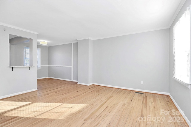 empty room featuring ornamental molding, light hardwood / wood-style floors, and a healthy amount of sunlight