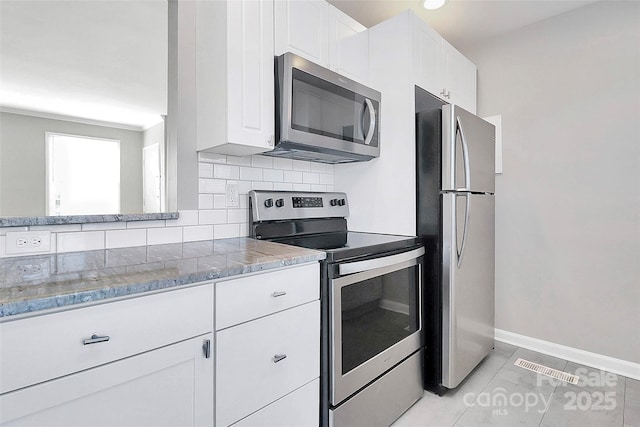 kitchen featuring tasteful backsplash, appliances with stainless steel finishes, light tile patterned floors, and white cabinets