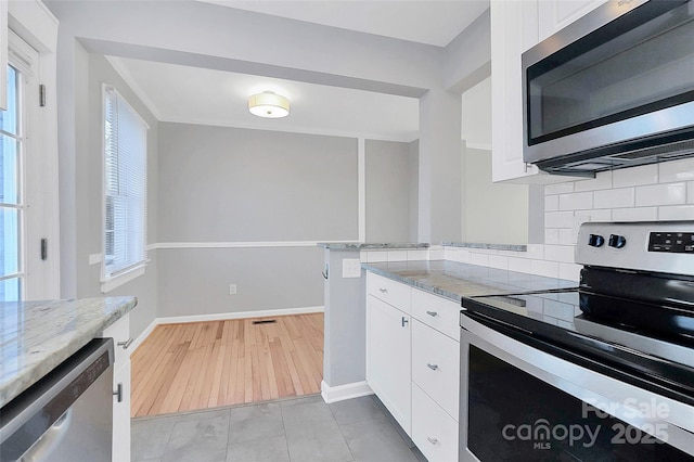 kitchen featuring light stone counters, decorative backsplash, white cabinets, and appliances with stainless steel finishes