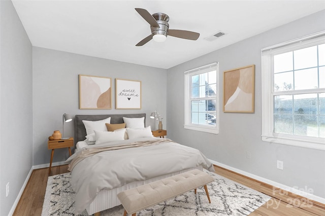 bedroom featuring multiple windows, wood-type flooring, and ceiling fan