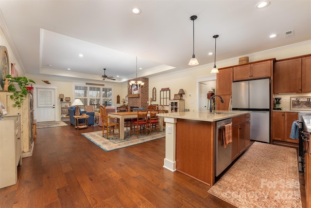 kitchen with sink, hanging light fixtures, a center island with sink, a tray ceiling, and stainless steel appliances