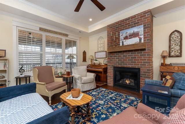 living room featuring ornamental molding, a brick fireplace, hardwood / wood-style floors, and ceiling fan