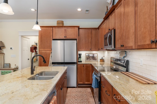 kitchen featuring sink, crown molding, appliances with stainless steel finishes, light stone countertops, and decorative light fixtures