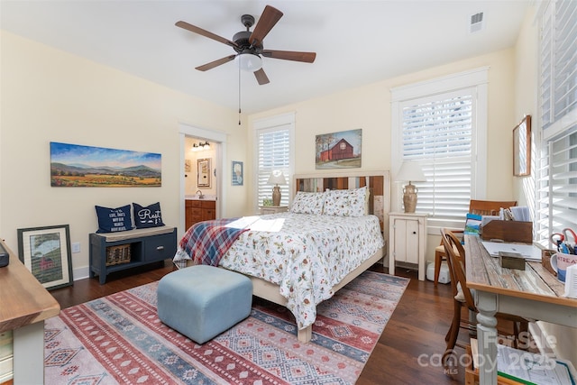 bedroom with multiple windows, ensuite bath, and dark hardwood / wood-style flooring