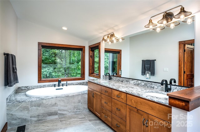 bathroom with lofted ceiling, tiled tub, and vanity