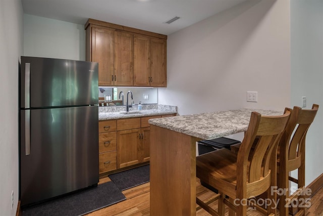 2126 Sycamore Dr, Nebo, NC 28761 - kitchen with freestanding refrigerator, light wood-style floors, brown cabinets, a sink, and a breakfast bar area