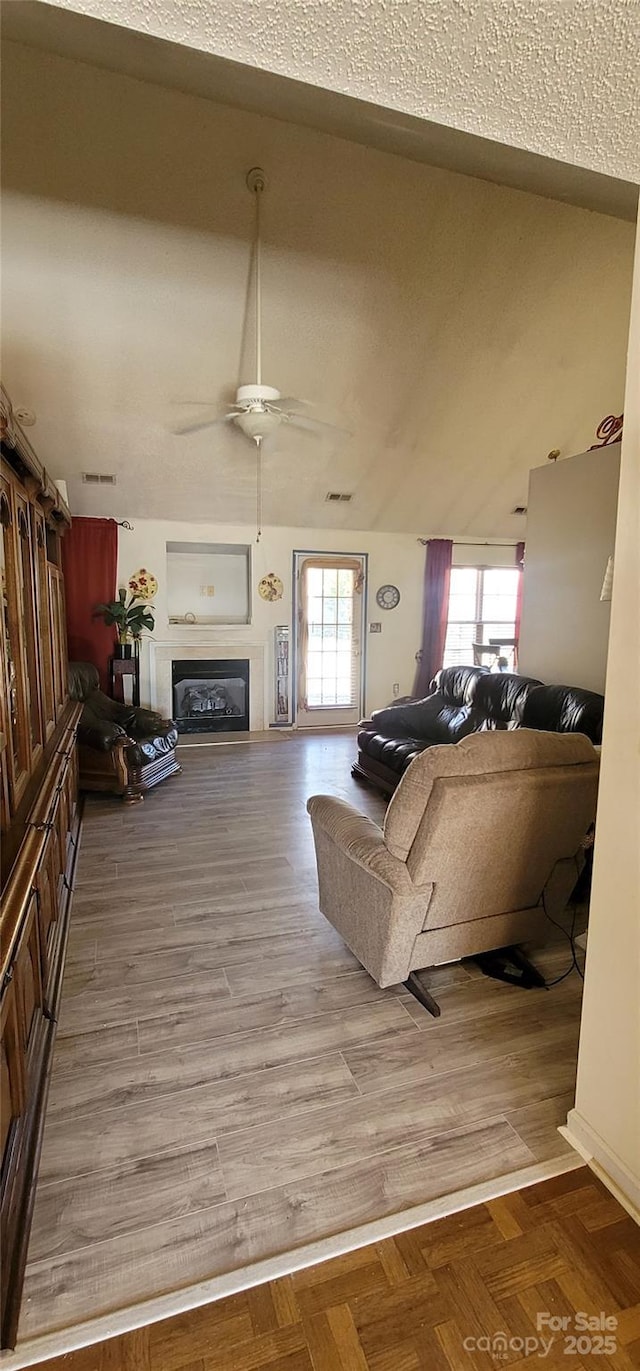 living room featuring light parquet floors, lofted ceiling, a wealth of natural light, and ceiling fan