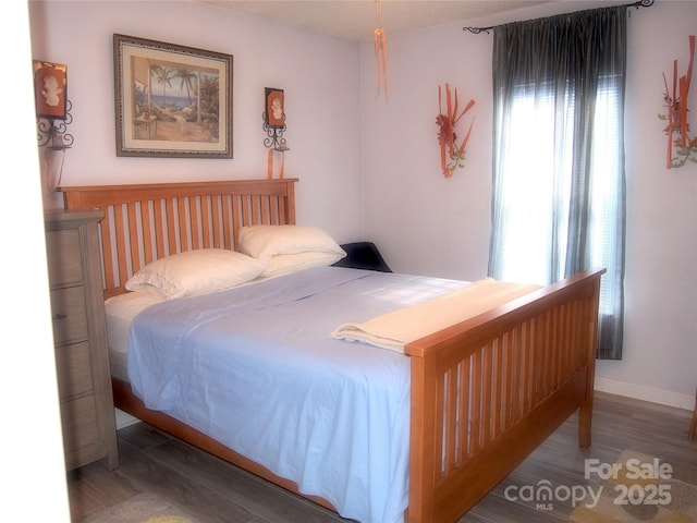 bedroom with multiple windows and dark hardwood / wood-style floors