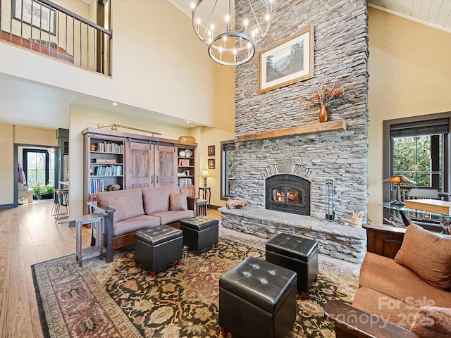 living room with an inviting chandelier, a fireplace, wood-type flooring, and a high ceiling