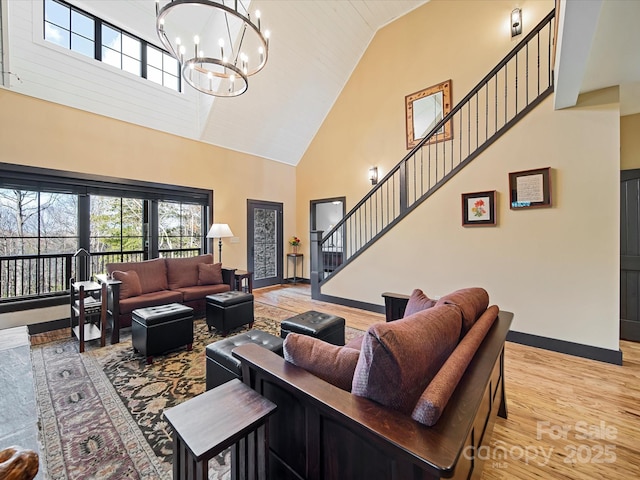 living room featuring a notable chandelier, light hardwood / wood-style flooring, and high vaulted ceiling