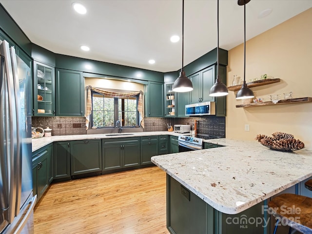 kitchen with sink, kitchen peninsula, pendant lighting, stainless steel appliances, and light stone countertops