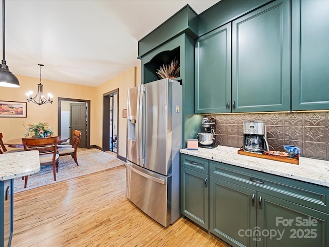 kitchen with pendant lighting, green cabinets, light hardwood / wood-style floors, and stainless steel refrigerator with ice dispenser