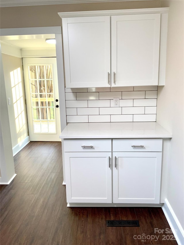 bar with white cabinetry, decorative backsplash, and dark hardwood / wood-style flooring