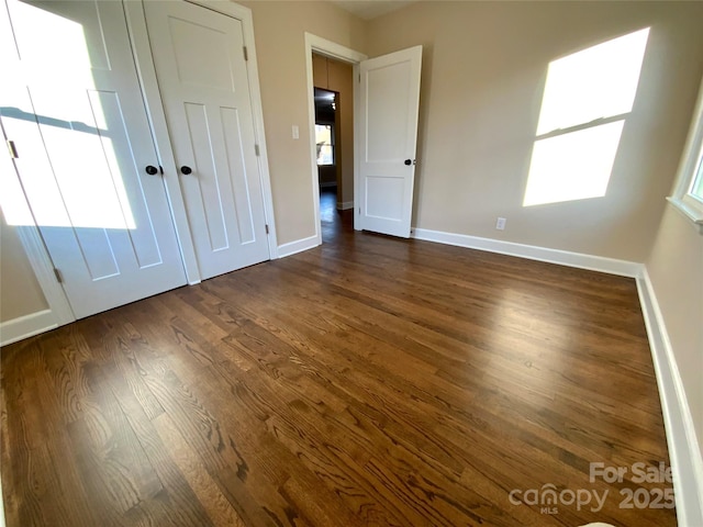 unfurnished bedroom featuring dark hardwood / wood-style floors and multiple windows