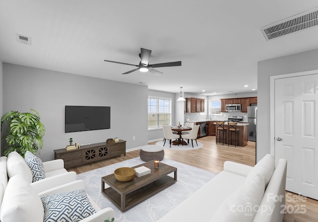 living area with ceiling fan, light wood-style flooring, and visible vents