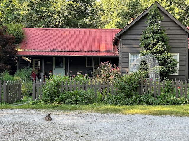 view of front of property with metal roof, a fenced front yard, and a chimney