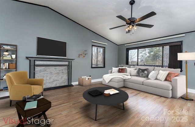 living room with hardwood / wood-style flooring, ceiling fan, lofted ceiling, and a fireplace