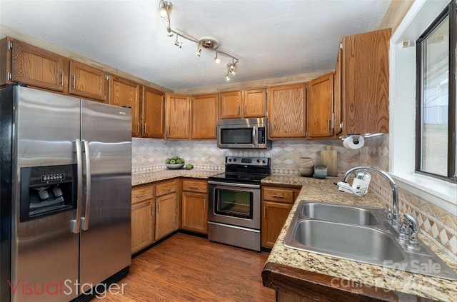 kitchen with sink, appliances with stainless steel finishes, a textured ceiling, dark hardwood / wood-style flooring, and decorative backsplash