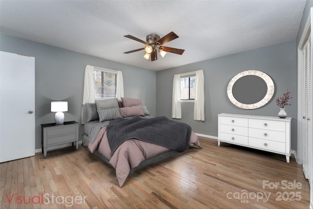 bedroom featuring a textured ceiling, light hardwood / wood-style floors, a closet, and ceiling fan