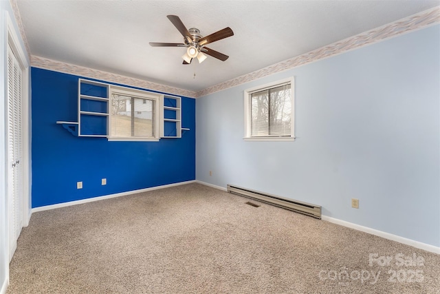 carpeted spare room with ceiling fan and a baseboard heating unit