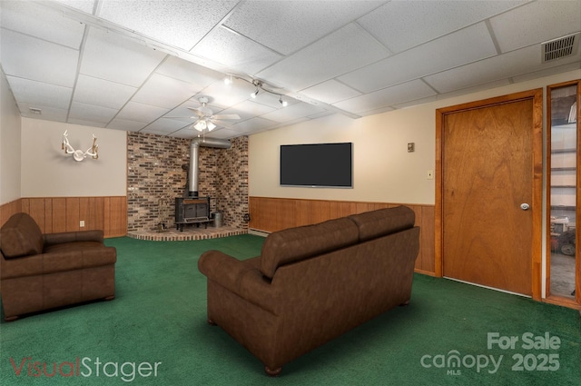 carpeted living room with a wood stove and a paneled ceiling