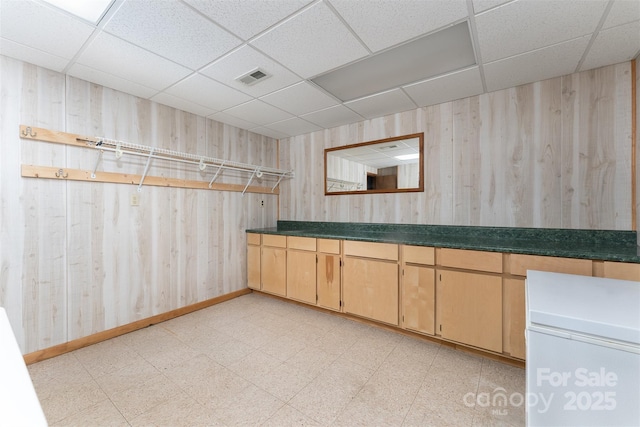 bathroom with a drop ceiling and wooden walls