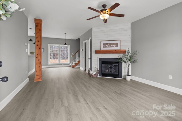 unfurnished living room featuring wood-type flooring, ceiling fan, and a fireplace